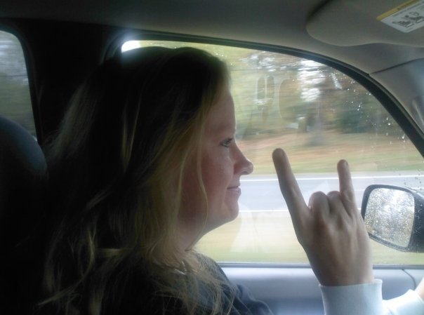 Debbie giving the rocker devil horns while driving