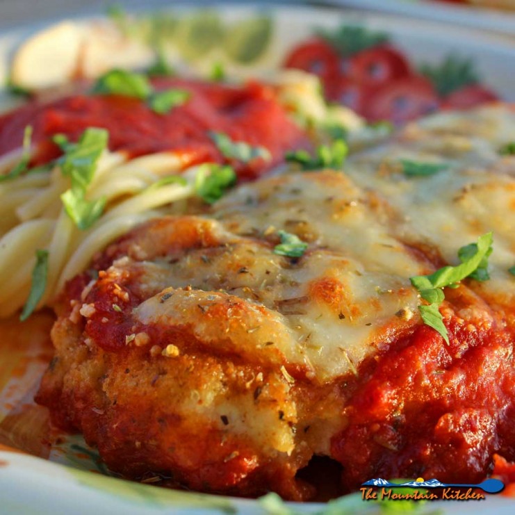 I practically drool just thinking about this delicious chicken parmesan. Lightly browned melted gooey cheese and fresh basil top these crispy breaded chicken breasts lying on a bed of tomato sauce with a side order of spaghetti. This is food that comforts the soul! | TheMountainKitchen.com