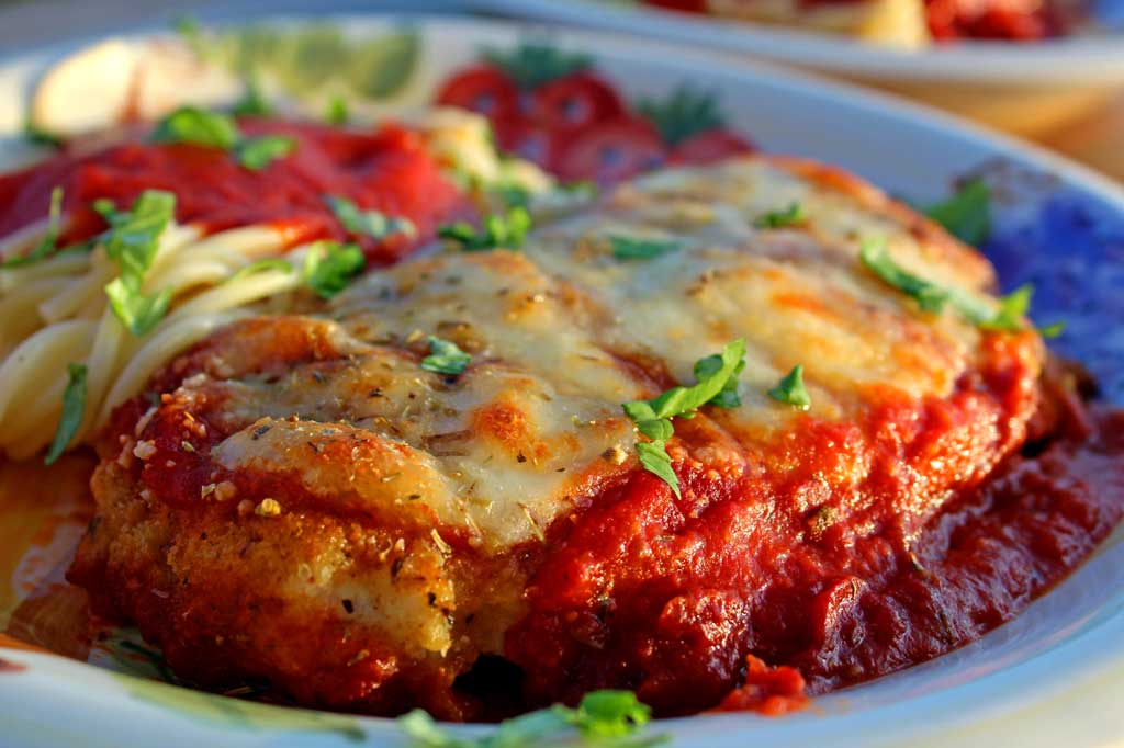 I practically drool just thinking about this delicious chicken parmesan. Lightly browned melted gooey cheese and fresh basil top these crispy breaded chicken breasts lying on a bed of tomato sauce with a side order of spaghetti. This is food that comforts the soul!