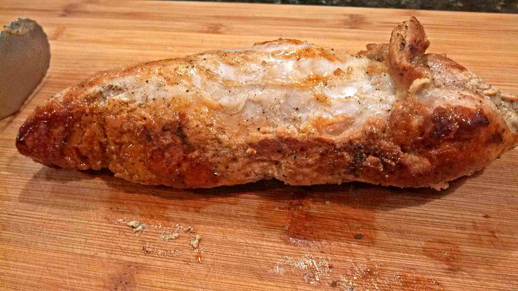 browned tenderloin resting on carving board
