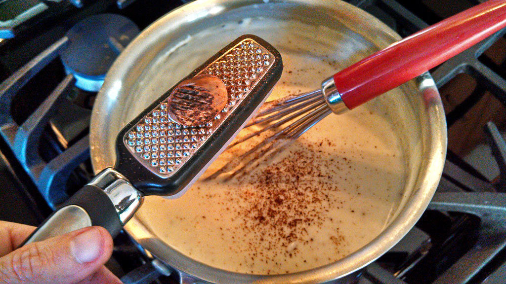 grating nutmeg into bechamel