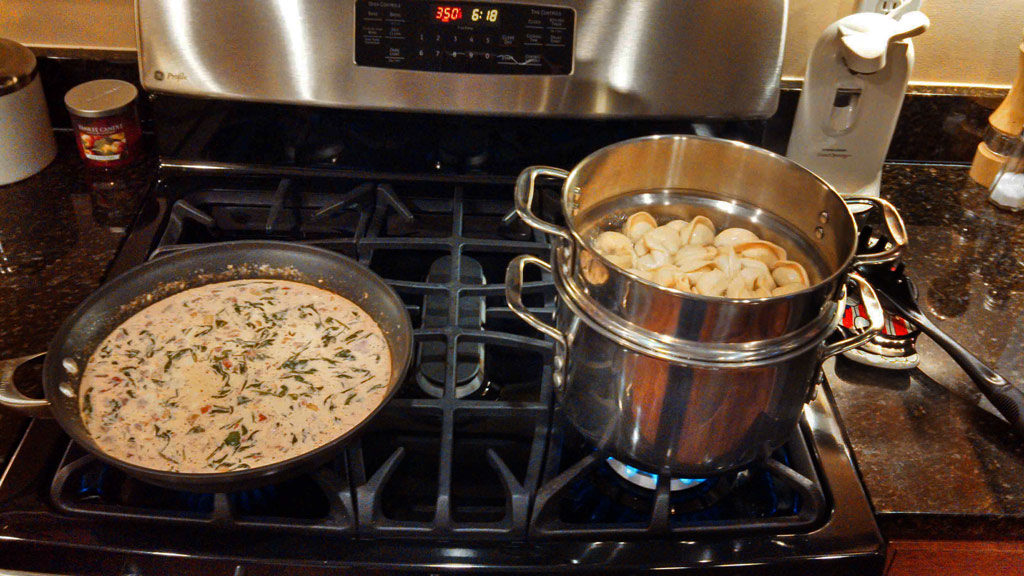 pasta in the pot and cream sauce ready for the pasta on the stove