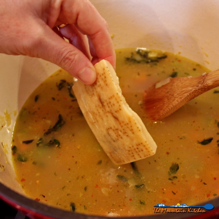 dropping cheese rind into pot of soup