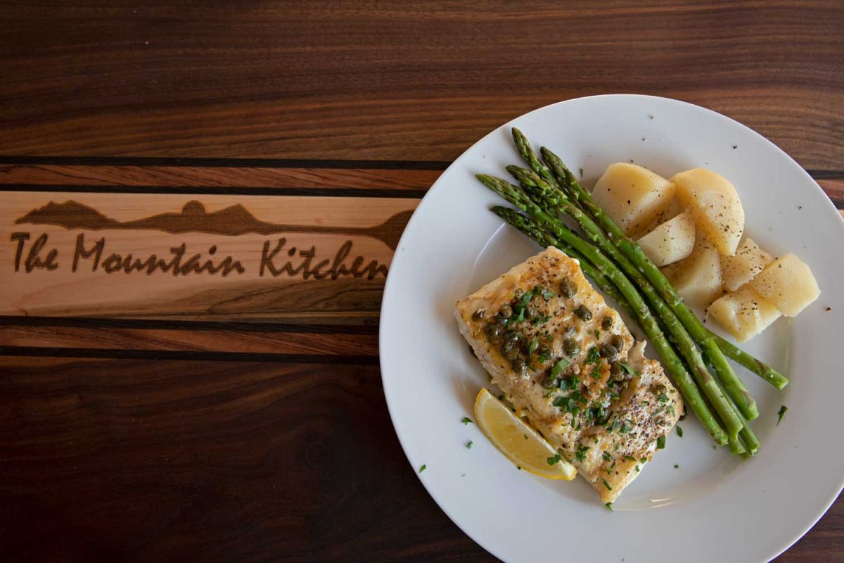 pan-seared halibut with caper butter sauce on plate with asparagus and potatoes