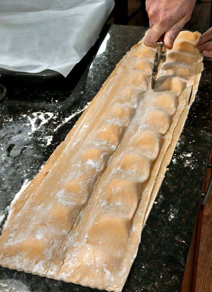 cutting ravioli from sheets of pasta