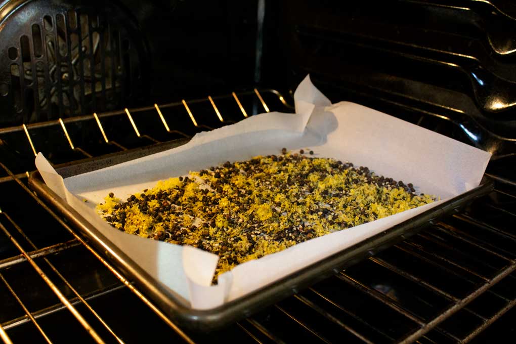 lemon zest and peppercorns on baking sheet in oven