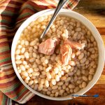 slow-cooker navy beans in bowl with ham and a spoon