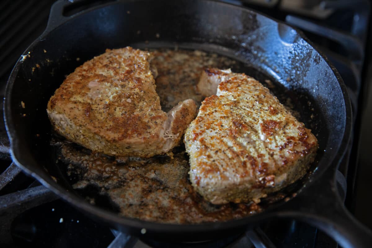 tuna steaks searing in cast iron pan