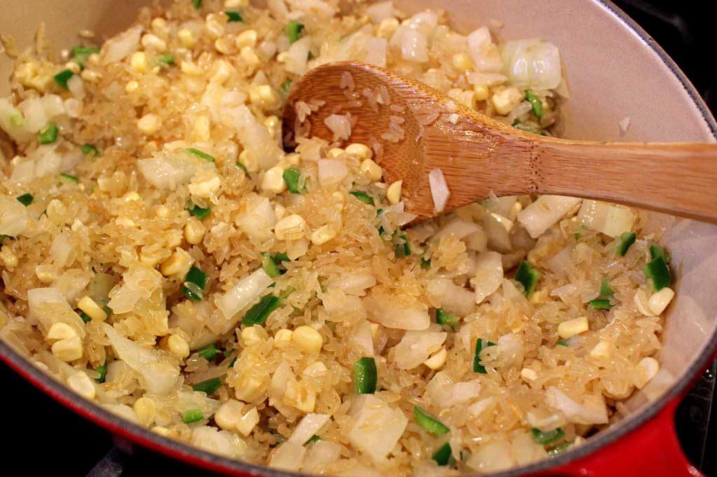 rice cooking in pot with onions and jalapeno