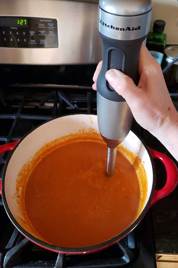 blending the roasted tomato soup with immersion blender