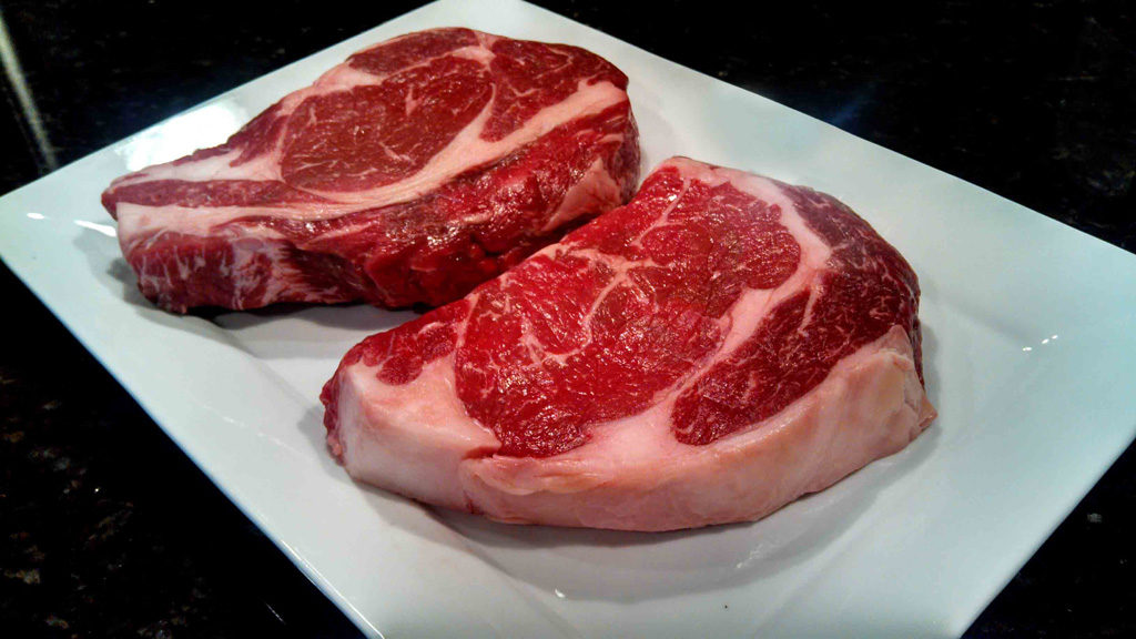 raw steaks on platter