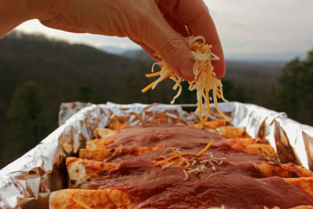sprinkling cheese on top of enchiladas