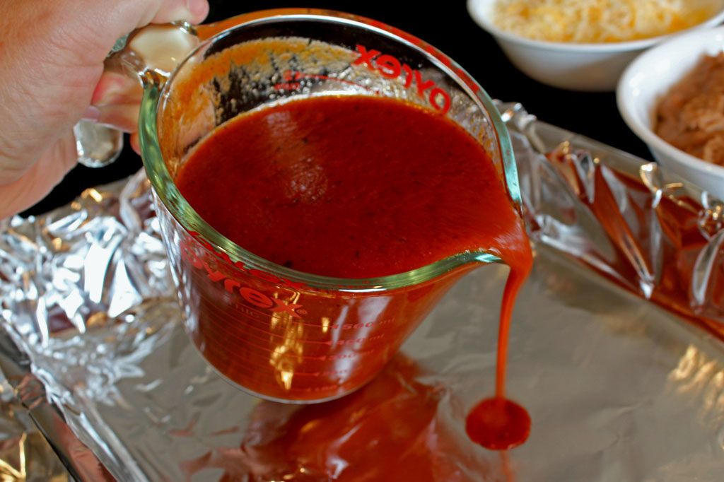 pouring enchilada sauce into pan