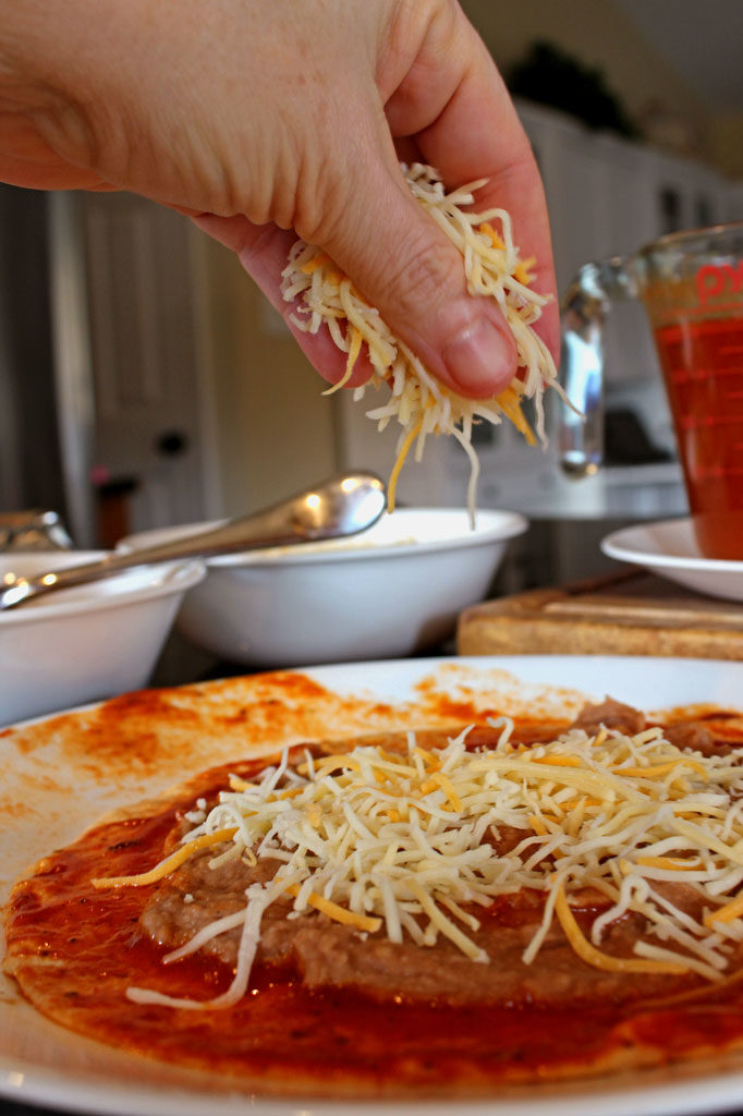 sprinkling cheese over sauce and tortilla