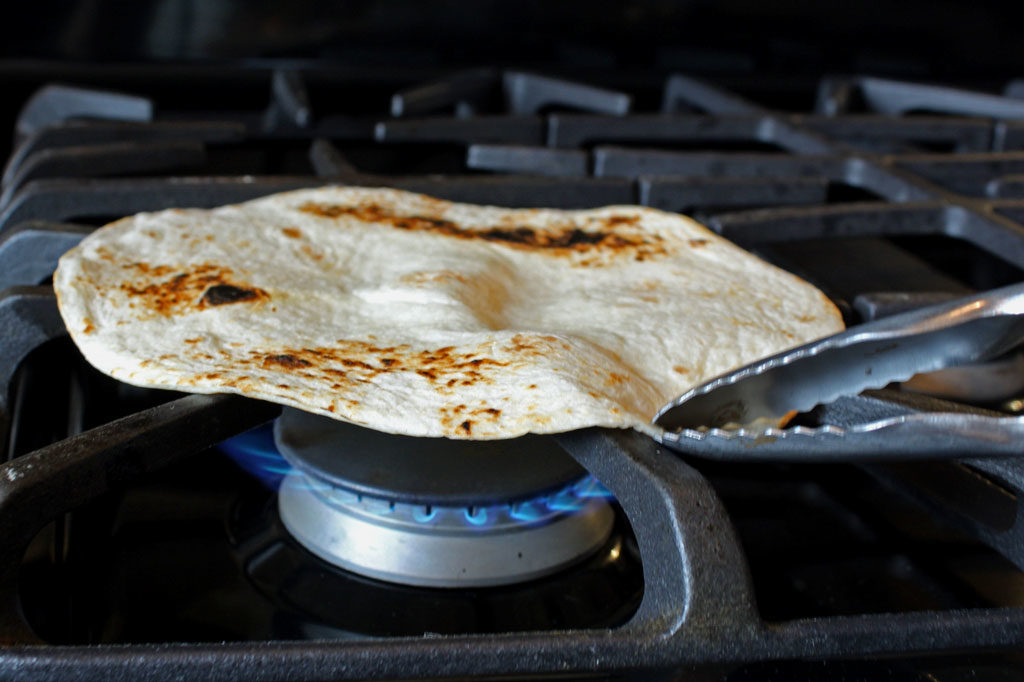 toasting tortilla over gas flame