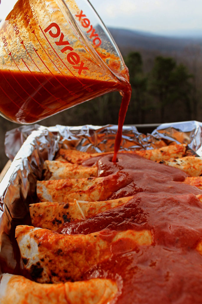 pouring enchilada sauce over enchiladas