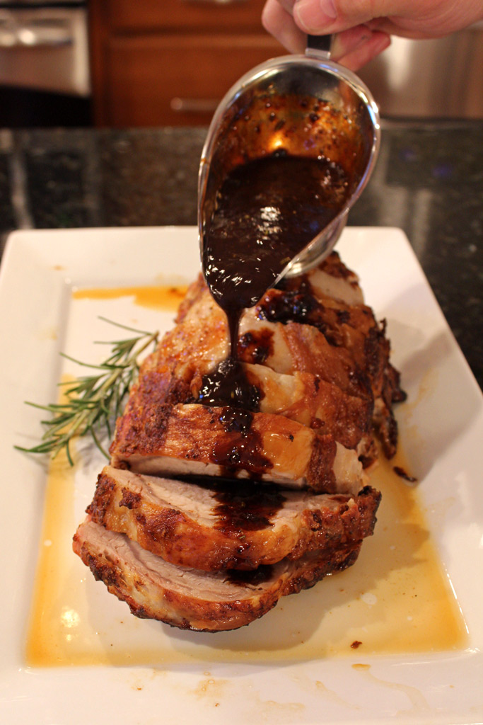 pouring sauce over Mustard-Maple Pork Ribeye Roast