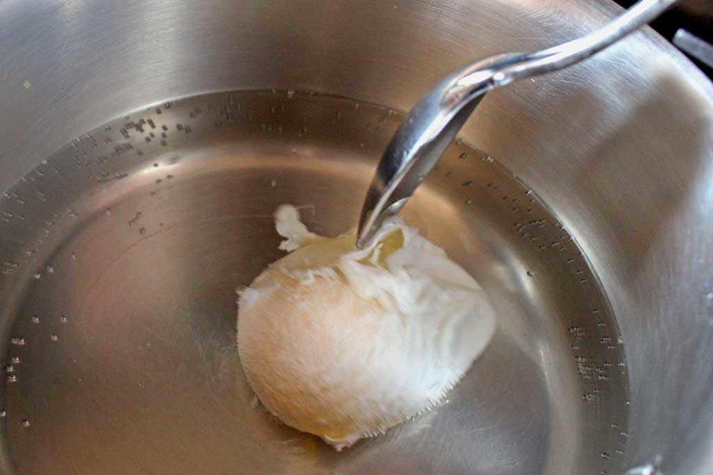 spooning white onto egg in pot