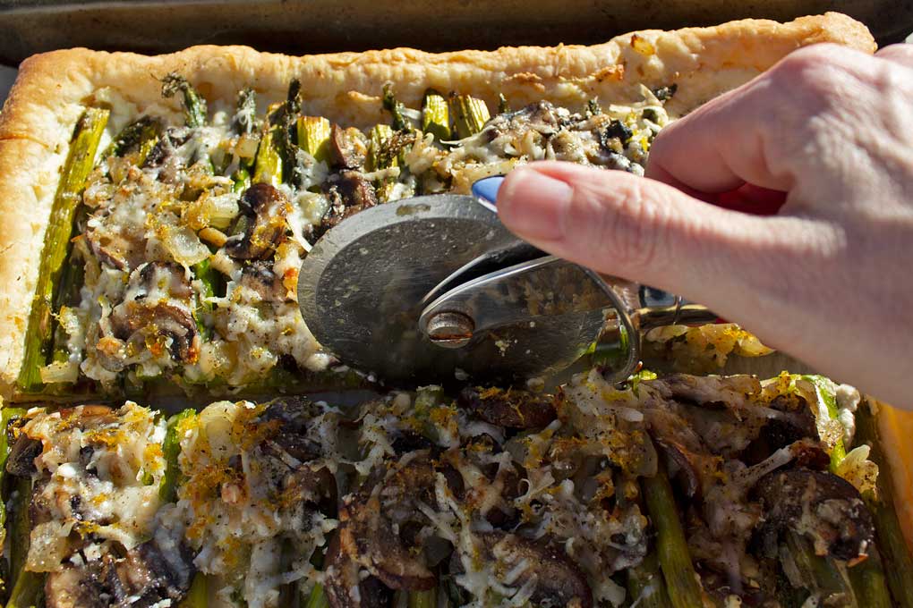 cutting asparagus-ricotta tart with pizza cutter