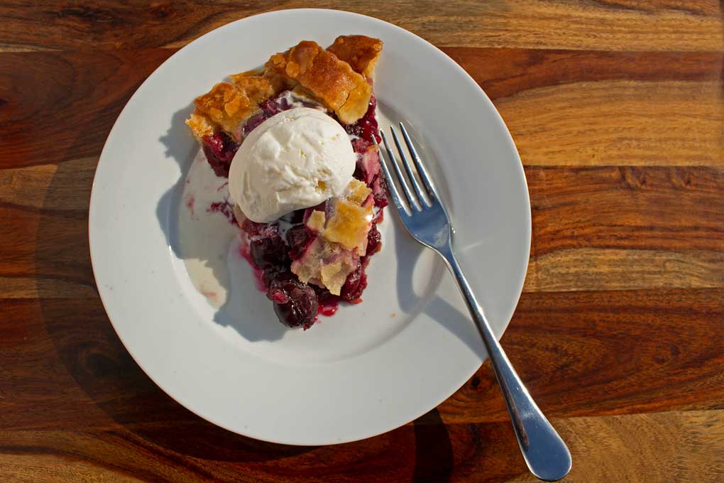 slice of homemade cherry pie with scoop of ice cream