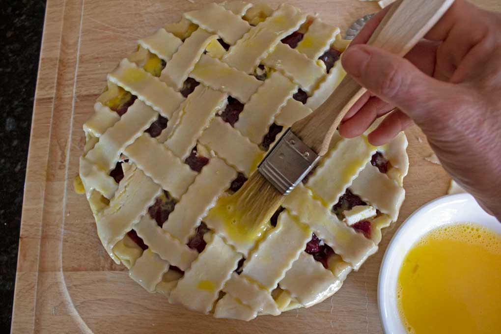 brushing egg wash onto lattice of pie