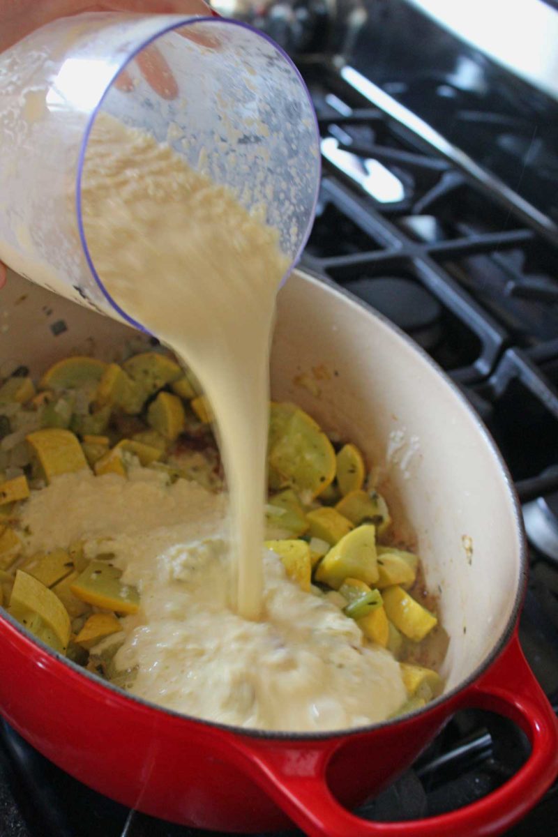 adding corn puree to vegetables in pot
