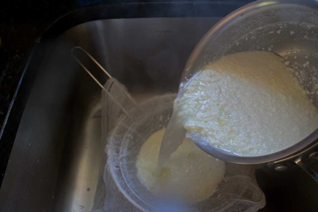 pouring ricotta into cheesecloth lined sieve