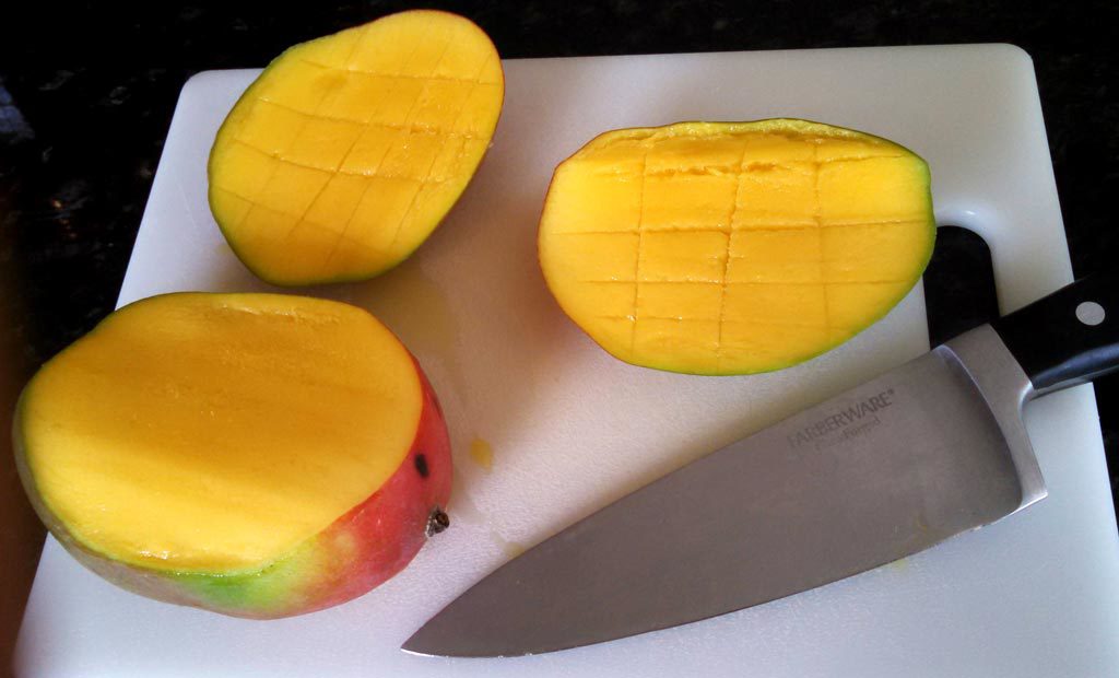 cut mango on cutting board with knife