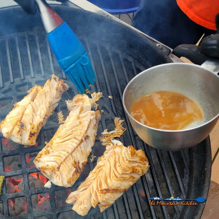 basting lemon butter sauce on grilling fish