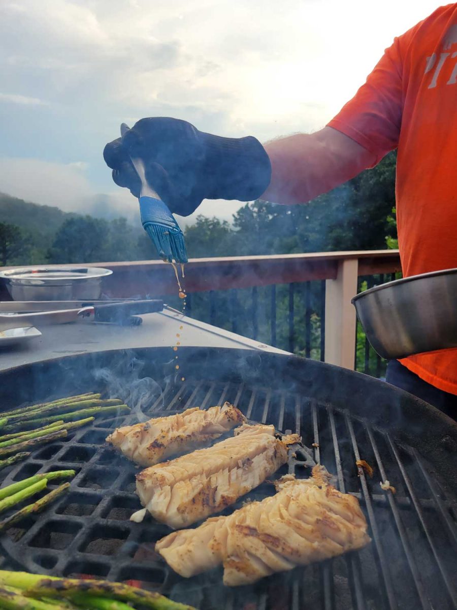 David brushing sauce onto grilling fish