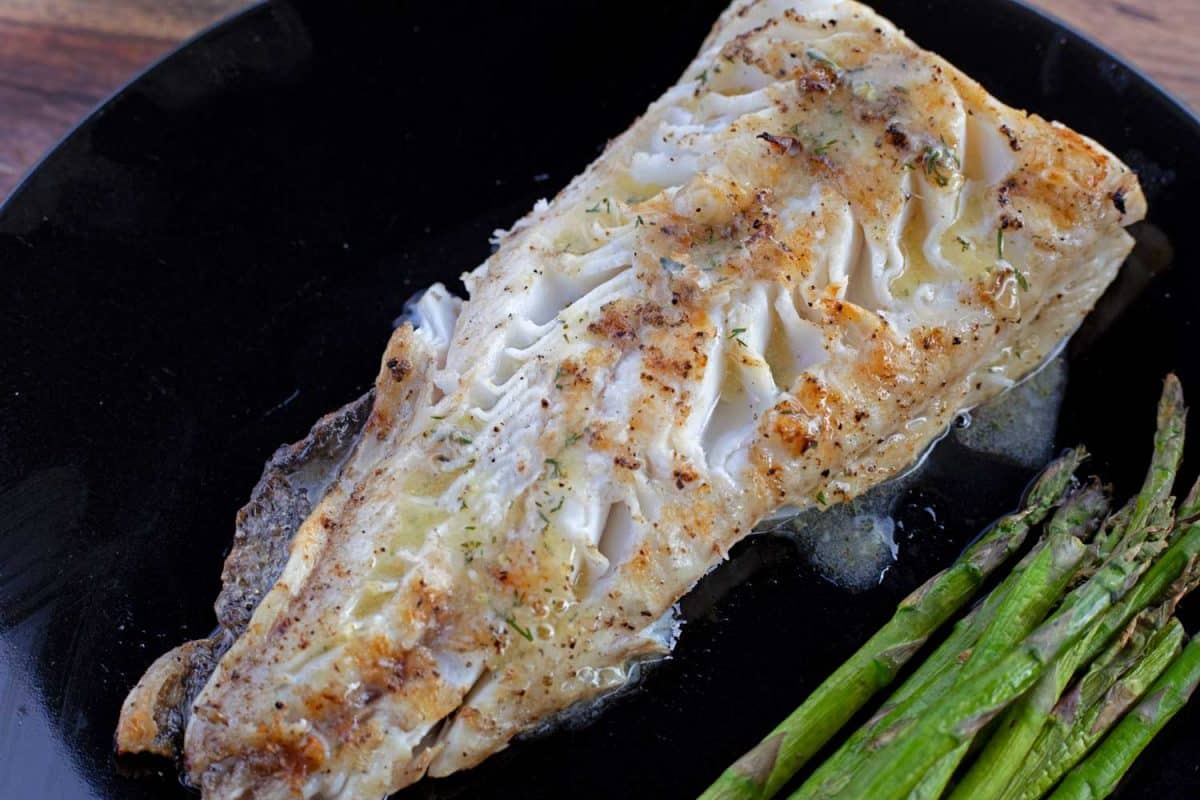 grilled fish on plate with asparagus