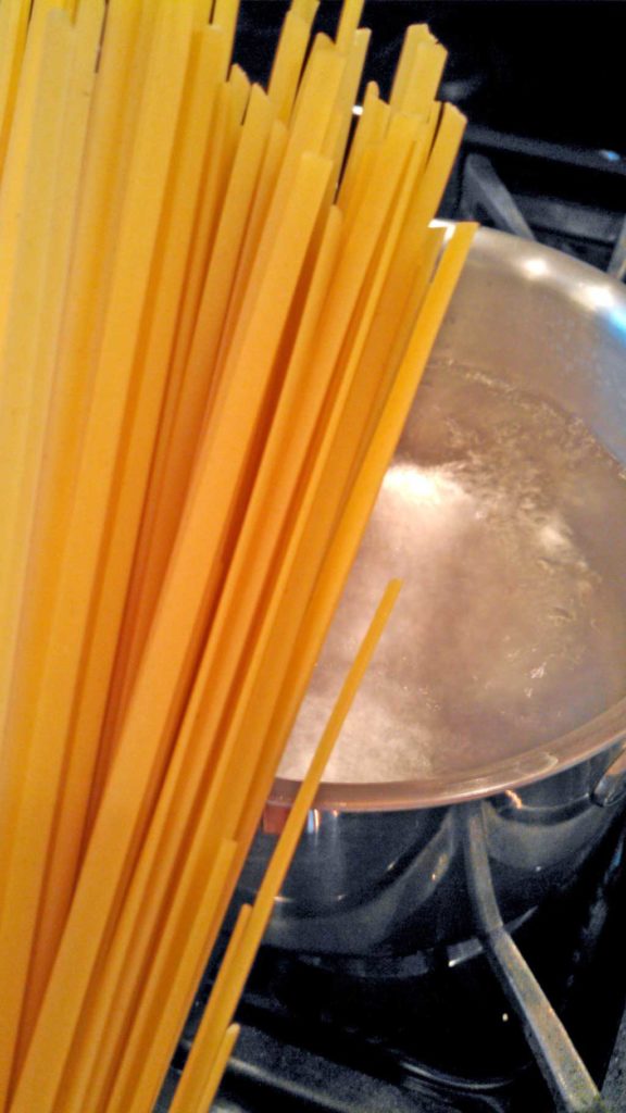 pasta getting ready to drop into boiling pot of water