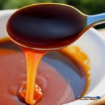 thick creamy caramel sauce oozing of spoon into bowl