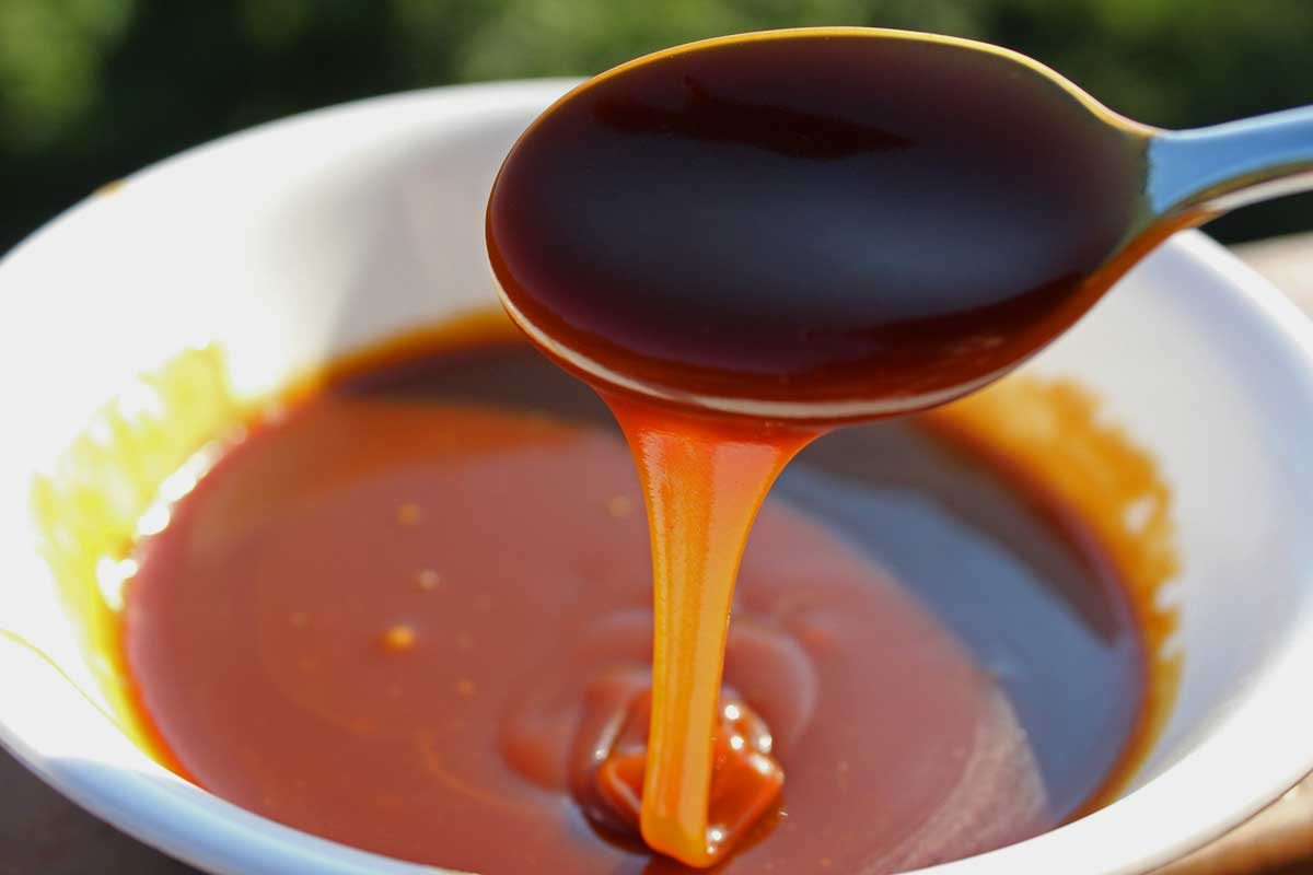 caramel sauce oozing off spoon into a bowl