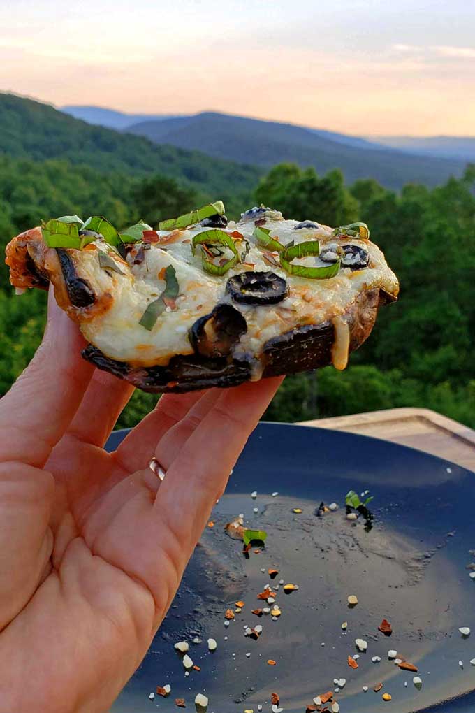 holding pizza in front of mountain view