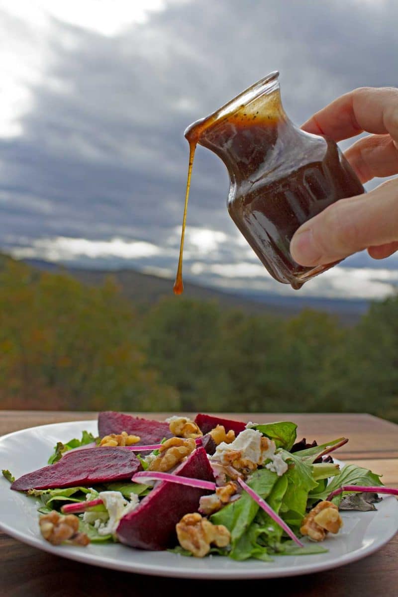plate of salad with dressing drizzling over top