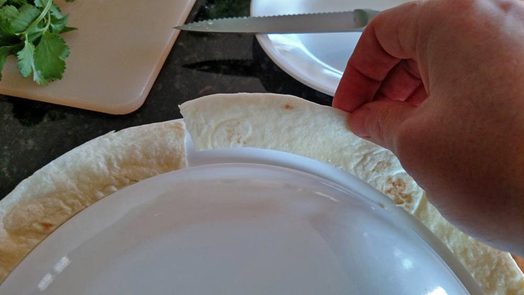 pulling trimmed tortilla away from plate