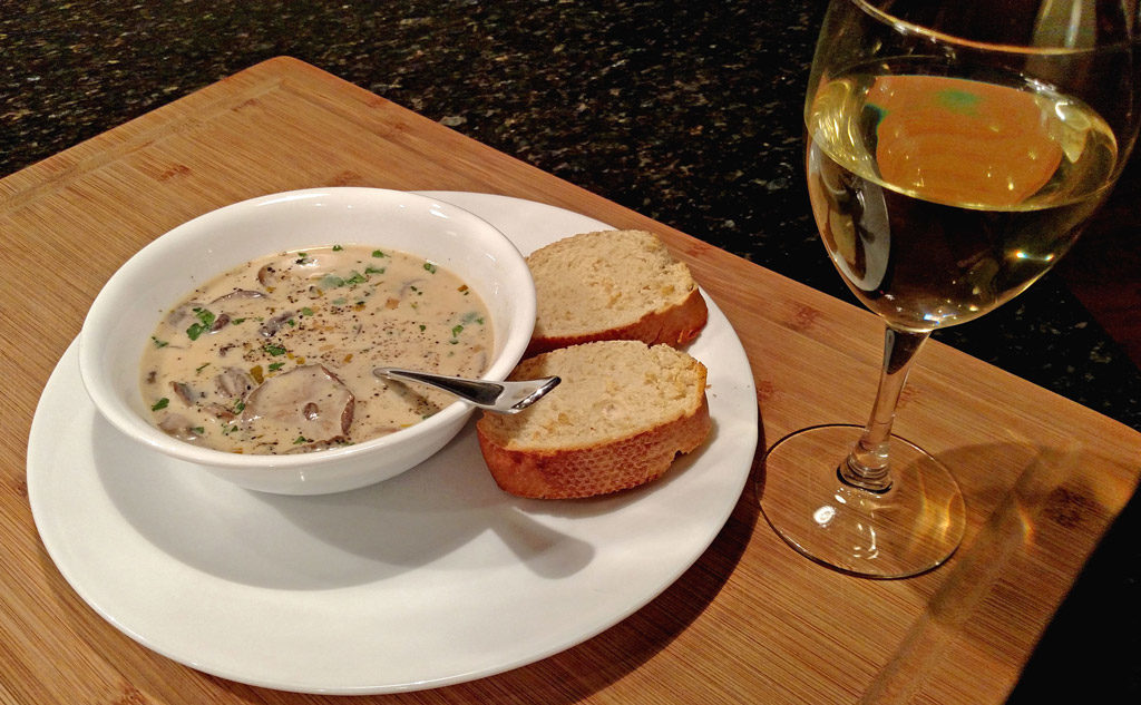 cream of mushroom soup in a bowl with bread and wine