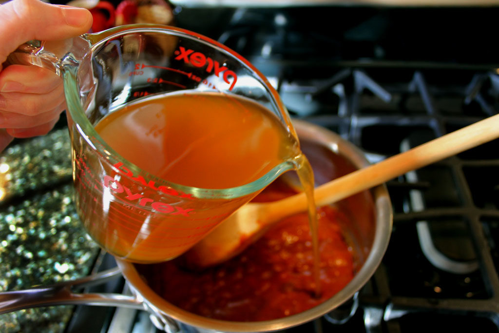 pouring broth into saucepan