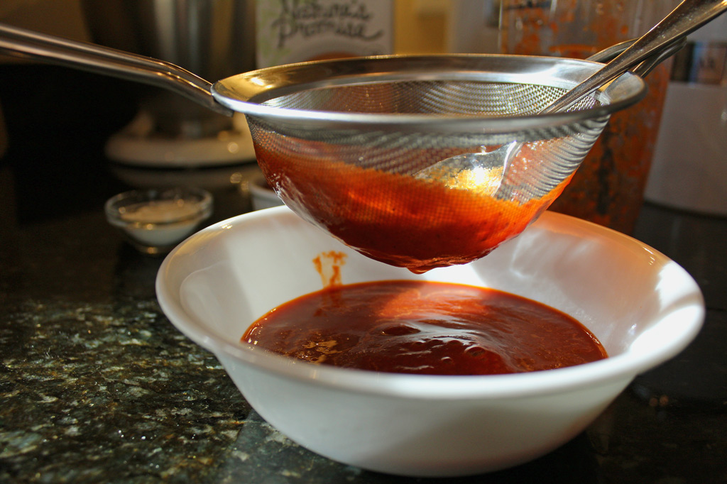 straining sauce through sieve