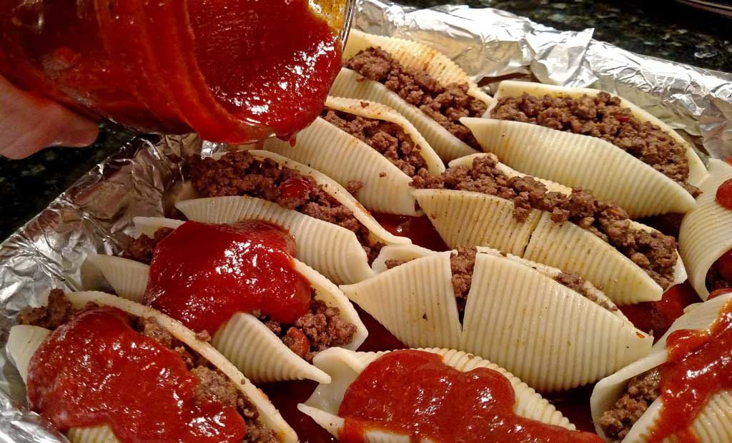 pouring sauce over pasta enchiladas