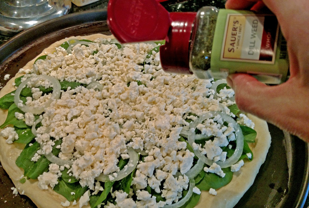 sprinkling dill onto pizza