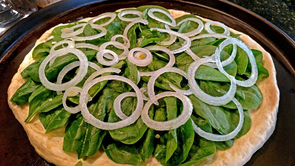 onions and spinach topping pizza dough