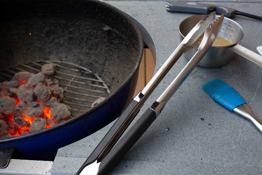 tongs bbq brush sauce pan and lighter beside grill