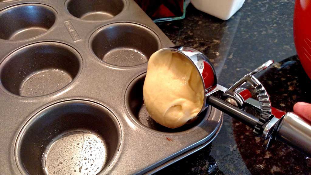 scooping the batter into the muffin tin