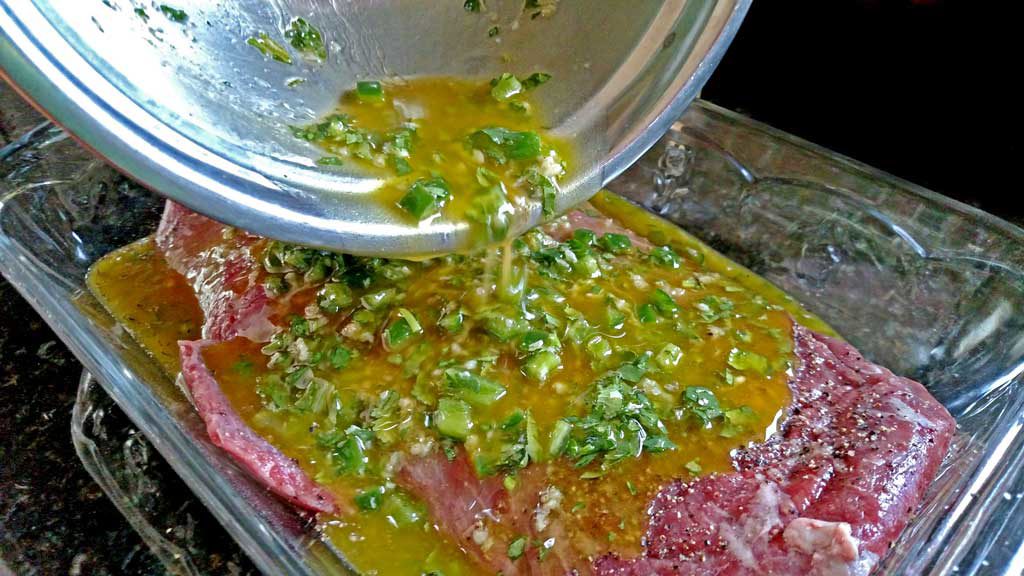 pouring marinade over flank steak in casserole dish