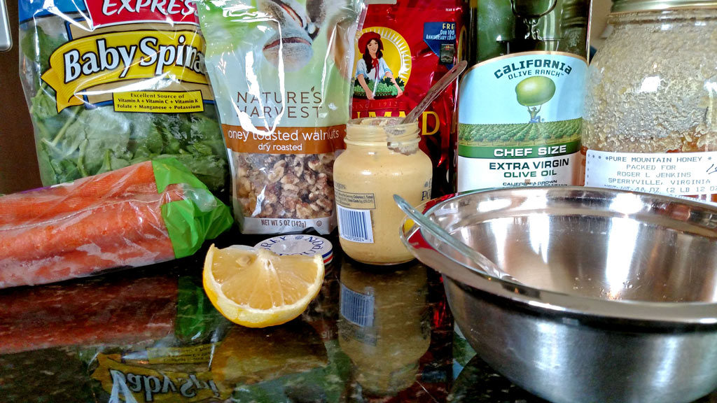 This healthy carrot salad with homemade dressing is served on top of a bed of spinach with juicy raisins, and candied walnuts. It was delicious! | TheMountainKitchen.com