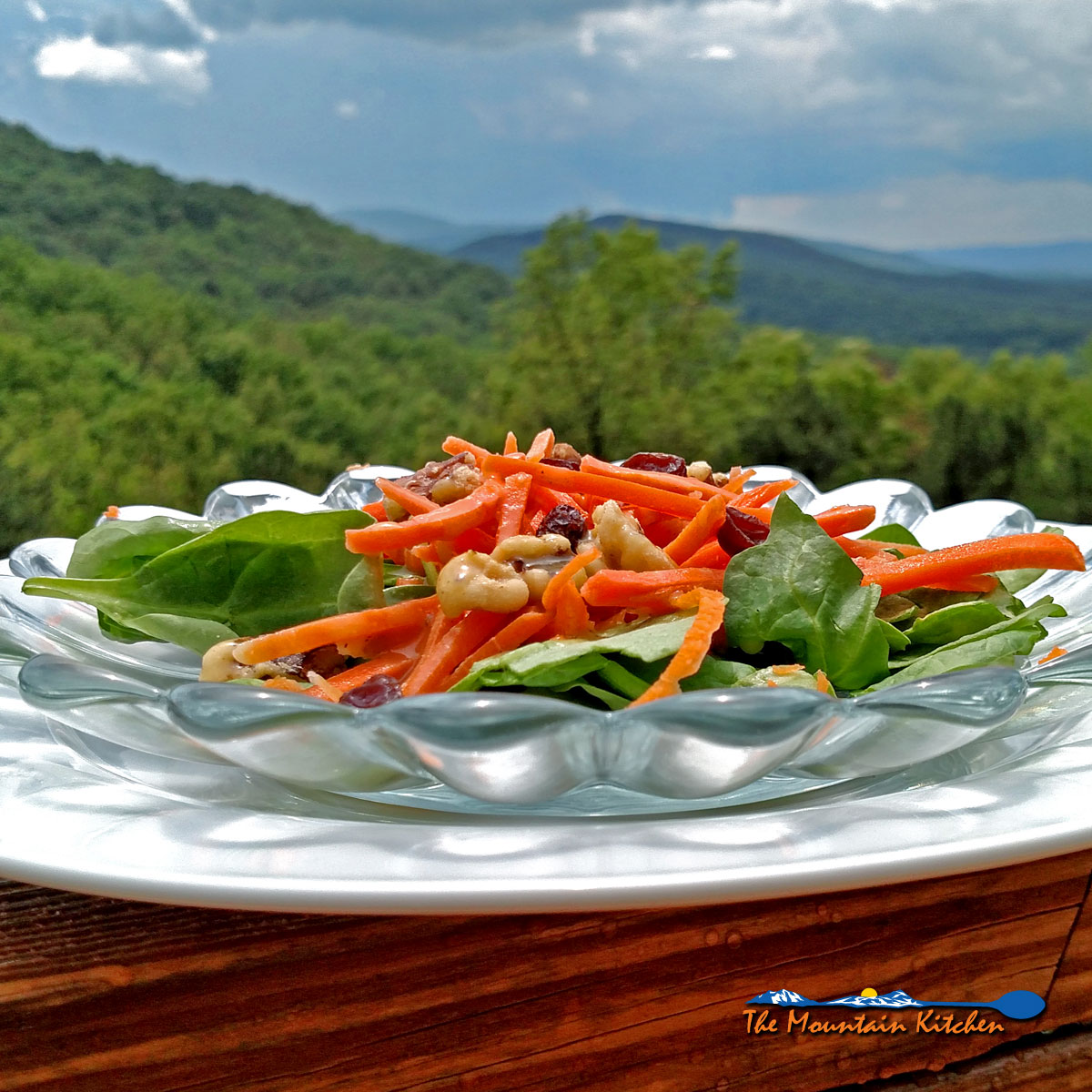 This healthy carrot salad with homemade dressing is served on top of a bed of spinach with juicy raisins, and candied walnuts. It was delicious! | TheMountainKitchen.com