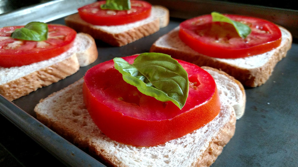 basil and tomato slices on top of slices of bread