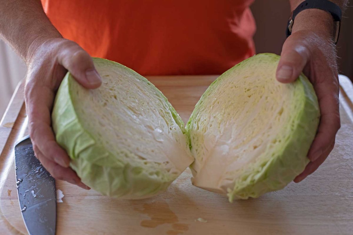 hands holding cabbage cut in half